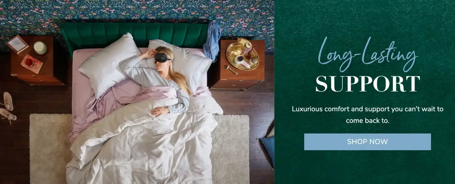 Woman sleeping in a luxurious bed with green headboard.